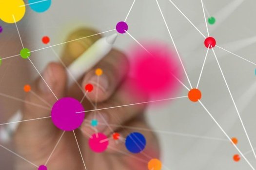 Eine Hand h&auml;lt einen Stift. Dieser Stift zeichnet bunte Punkte auf eine Oberfl&auml;che.