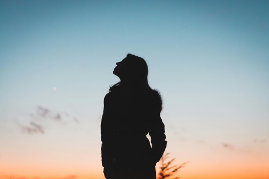 Eine Silouette einer Frau. Sie schaut in den Himmel.